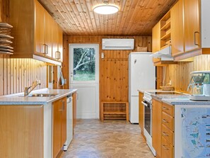 Eine kleine Küche mit Holzausstattung, einem eingebauten Backofen und einem Fenster mit Blick auf Bäume.