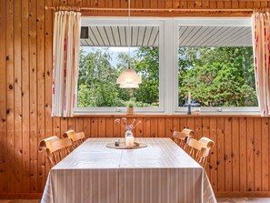 A dining area with a table set for four, wooden walls, and a window with curtains. - "Iivo" - 3.5km from the sea by Interhome (Rømø)
