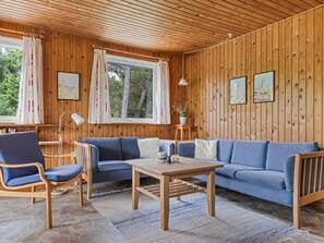 Ein gemütliches Zimmer mit Holzbalkendecke, einem blauen Sofa, einem Holztisch und einem Steinfußboden.
