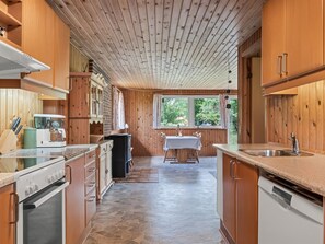 A kitchen with wooden cabinets, a stove, and a dining area with a table and chairs. - "Iivo" - 3.5km from the sea by Interhome (Rømø)