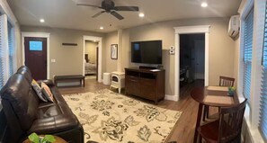 A living room with a sofa, a coffee table, a TV, and a dining area with a table and chairs. - Westside light and bright Guesthouse. Private entrance, this is NOT a basement (Idaho Falls)