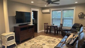 A living room with a television, a fireplace, a dining area with chairs, and a leather sofa. - Westside light and bright Guesthouse. Private entrance, this is NOT a basement (Idaho Falls)