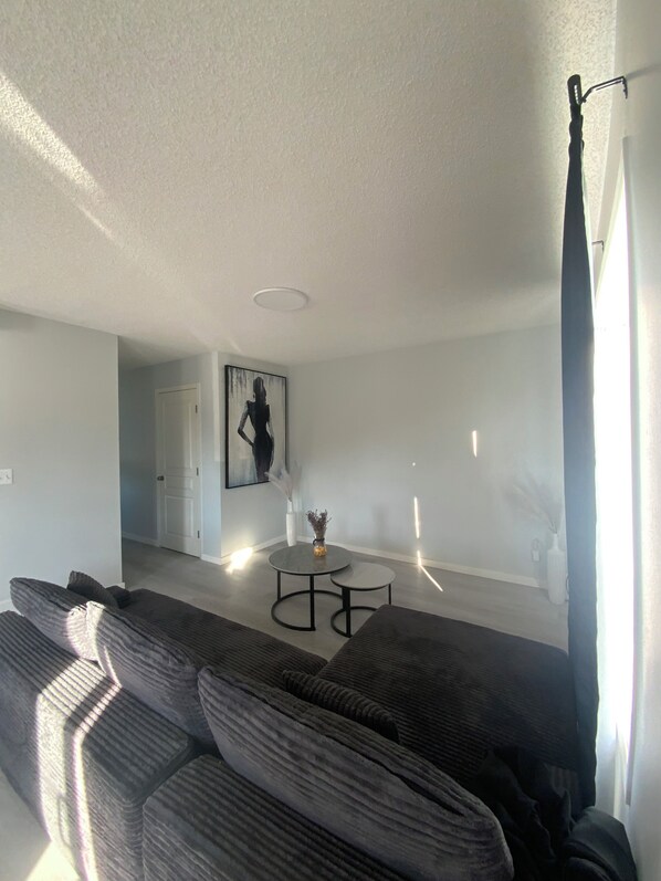 A modern living room with a sectional sofa, a small round coffee table, and a painting on the wall.