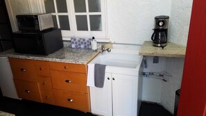 A compact kitchen with a microwave, coffee maker, and a sink.