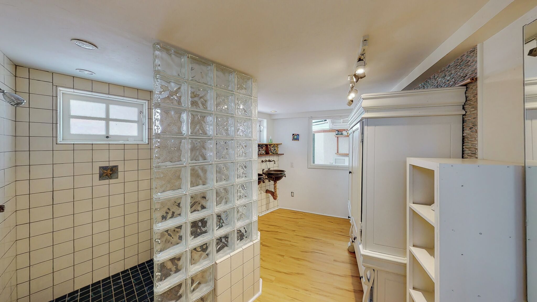 A kitchen with a tiled backsplash, wooden flooring, and a window.