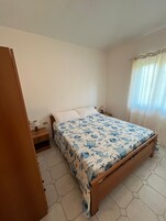 Un dormitorio con cama, mesita de noche y ventana con cortinas.