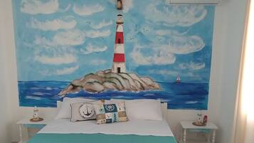 Una camera da letto con un letto, un comodino, un tavolino, un quadro raffigurante un faro e un condizionatore d'aria.