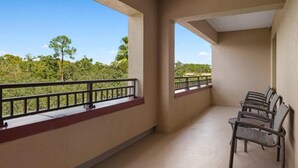 Ein Balkon mit Blick auf Bäume und einen klaren Himmel.