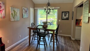 A dining area with a wooden table and chairs, a chandelier, and artwork on the walls. - 2BR Charlevoix Getaway - Walk to Lake Michigan Beach - Dog Friendly (Charlevoix)