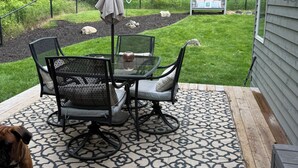 An outdoor patio with a table and chairs, a dog, a small shed, and a fenced garden area. - 2BR Charlevoix Getaway - Walk to Lake Michigan Beach - Dog Friendly (Charlevoix)