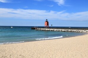 A beach with a lighthouse, clear skies, and calm sea. - 2BR Charlevoix Getaway - Walk to Lake Michigan Beach - Dog Friendly (Charlevoix)