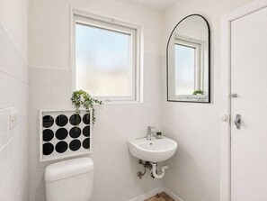Un baño con inodoro, lavamanos, ventana y espejo.