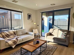 Ein Wohnzimmer mit zwei Sofas, einem Couchtisch und Blick durch eine Glasschiebetür.
