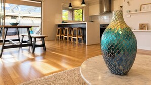 Eine moderne Küche mit Essbereich, eine große Vase auf einem Tisch und Blick ins Freie.
