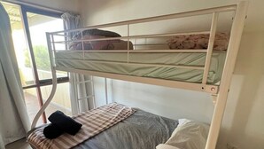 A bunk bed with a window, a bedspread, and pillows. - Retro Beach Shack in the Heart of Rye (Rye)