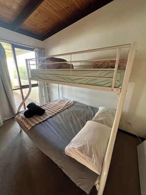 A bunk bed with a window, a bedspread, and pillows. - Retro Beach Shack in the Heart of Rye (Rye)