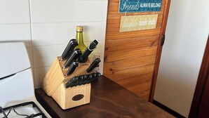 A kitchen with a gas stove, a knife block, and a wooden door with motivational signs. - Retro Beach Shack in the Heart of Rye (Rye)