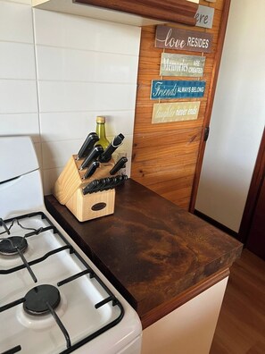 A kitchen with a gas stove, a knife block, and a wooden door with motivational signs. - Retro Beach Shack in the Heart of Rye (Rye)