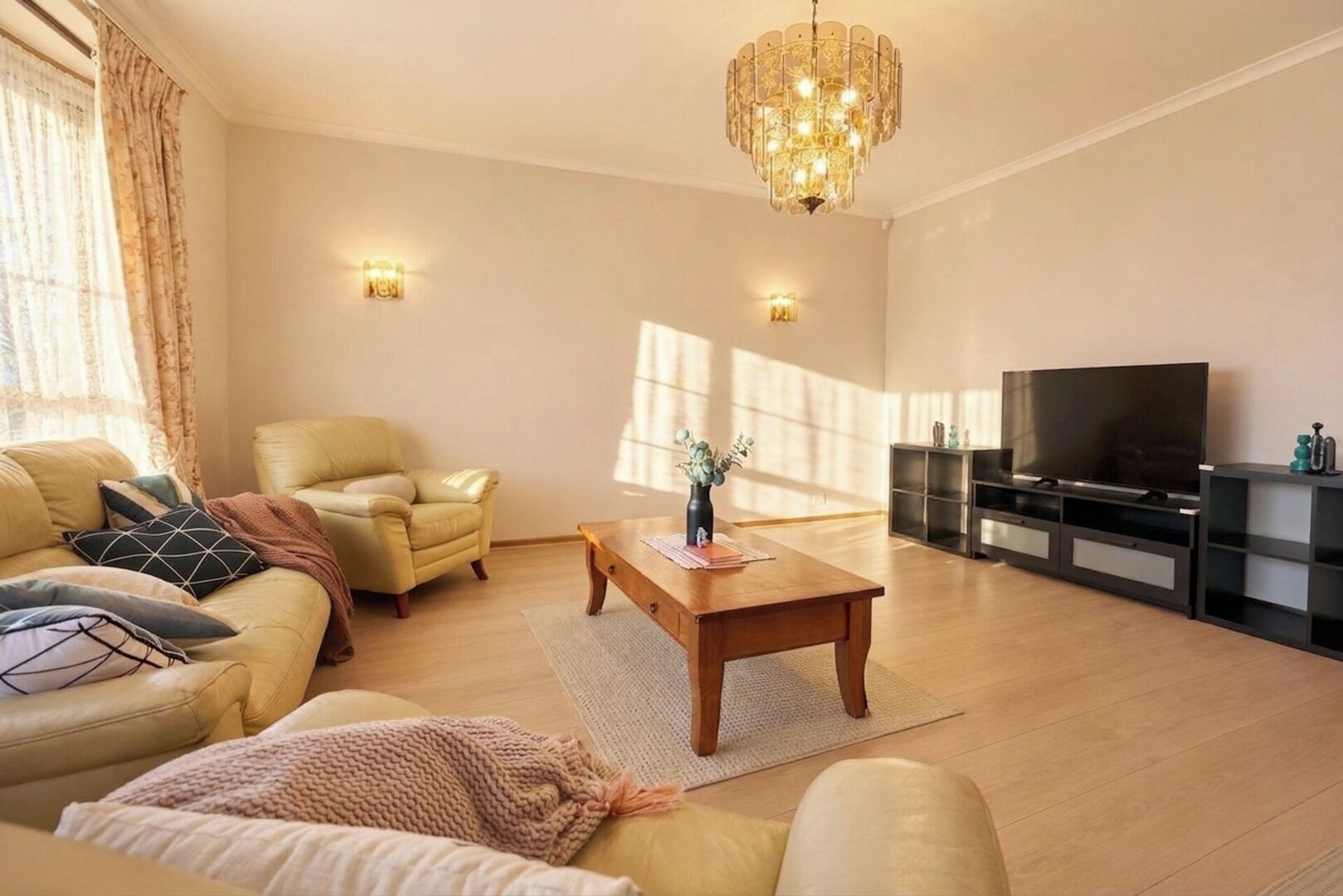 A living room with a sofa, armchair, coffee table, TV stand, and decorative items.