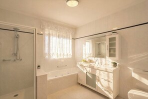 A modern bathroom with a glass-enclosed shower, a large bathtub, a vanity with a mirror, and a toilet. - 4BR Home Near Altona Beach · Sleeps 9 · Yard (Altona Meadows)