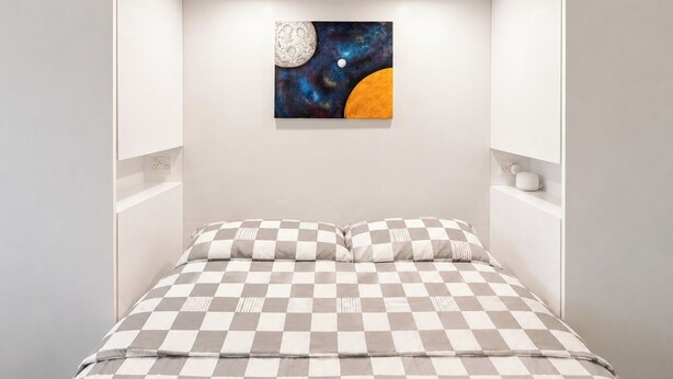 A bedroom with a checkered bedspread, a painting of celestial bodies, and a white headboard. - Compact Stay with Balcony, Rooftop and Gym (West Melbourne)