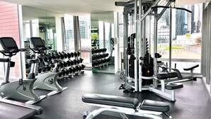 A modern gym with cardio machines, free weights, and a squat rack. - Compact Stay with Balcony, Rooftop and Gym (West Melbourne)