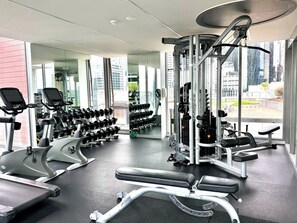 A modern gym with cardio machines, free weights, and a squat rack. - Compact Stay with Balcony, Rooftop and Gym (West Melbourne)