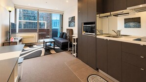 A modern kitchen with dark cabinetry, a built-in microwave, and a stainless steel sink. - Compact Stay with Balcony, Rooftop and Gym (West Melbourne)
