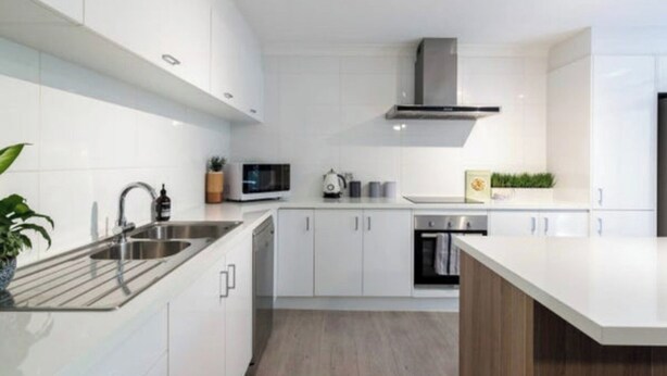 A modern kitchen with white cabinetry, stainless steel appliances, and a central island. - Location, Location...This seaside unit has it all (Surfers Paradise)