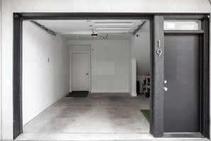 A garage entrance with a closed door, a no-smoking sign, and a fire extinguisher. - The Nest, TC Downtown + Beach, Rooftop + Garage (Traverse City)