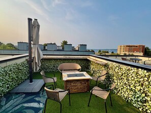A rooftop terrace with a table and chairs, a small pool, and a view of the sea. - The Nest, TC Downtown + Beach, Rooftop + Garage (Traverse City)