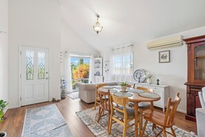 A dining area with a wooden table and chairs, a white cabinet, and a ceiling light fixture.