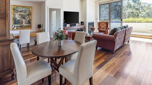 A spacious living area with a dining table, chairs, a sofa, and a television. - Bright and Spacious Penthouse by Parliament House (Forrest)