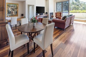 A spacious living area with a dining table, chairs, a sofa, and a television. - Bright and Spacious Penthouse by Parliament House (Forrest)