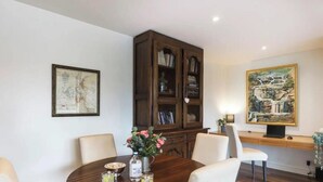 A dining area with a wooden table, chairs, a cabinet, and artwork on the walls. - Bright and Spacious Penthouse by Parliament House (Forrest)