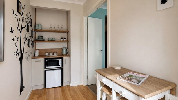 Una cocina compacta equipada con microondas, cafetera y estantes con utensilios de cocina.