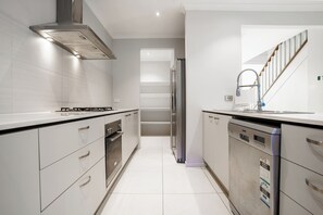 A modern kitchen with stainless steel appliances, white cabinetry, and a tiled backsplash. - Spacious Point Cook Retreat w/ Free Parking (Point Cook)