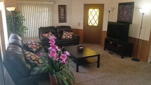 A living room with a sofa, coffee table, and a television. - Charming 55+ Arizona Getaway (Mesa)