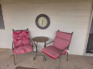 Two chairs with patterned cushions and a small round table, positioned on a porch with a clock on the wall. - Charming 55+ Arizona Getaway (Mesa)