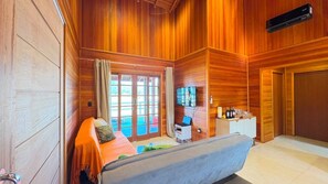 A wooden-paneled room with a bed, a TV, and a desk with a computer.