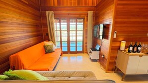 Un interno accogliente in legno con un divano, una scrivania con un portatile e un angolo bar con bottiglie.