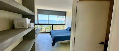 Une chambre avec un lit, une fenêtre donnant sur la mer et une étagère avec des serviettes.