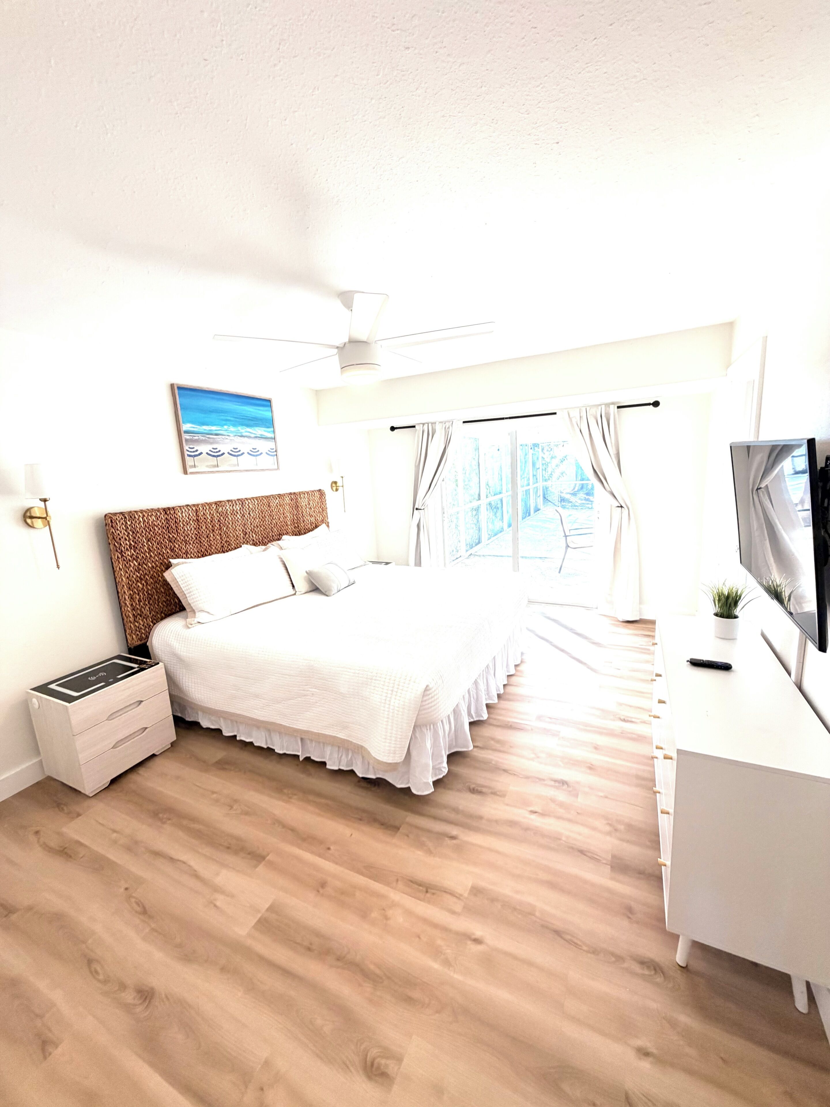 Ein Schlafzimmer mit einem Bett, einem Nachttisch, einem Fernseher und einem Fenster mit Vorhängen.