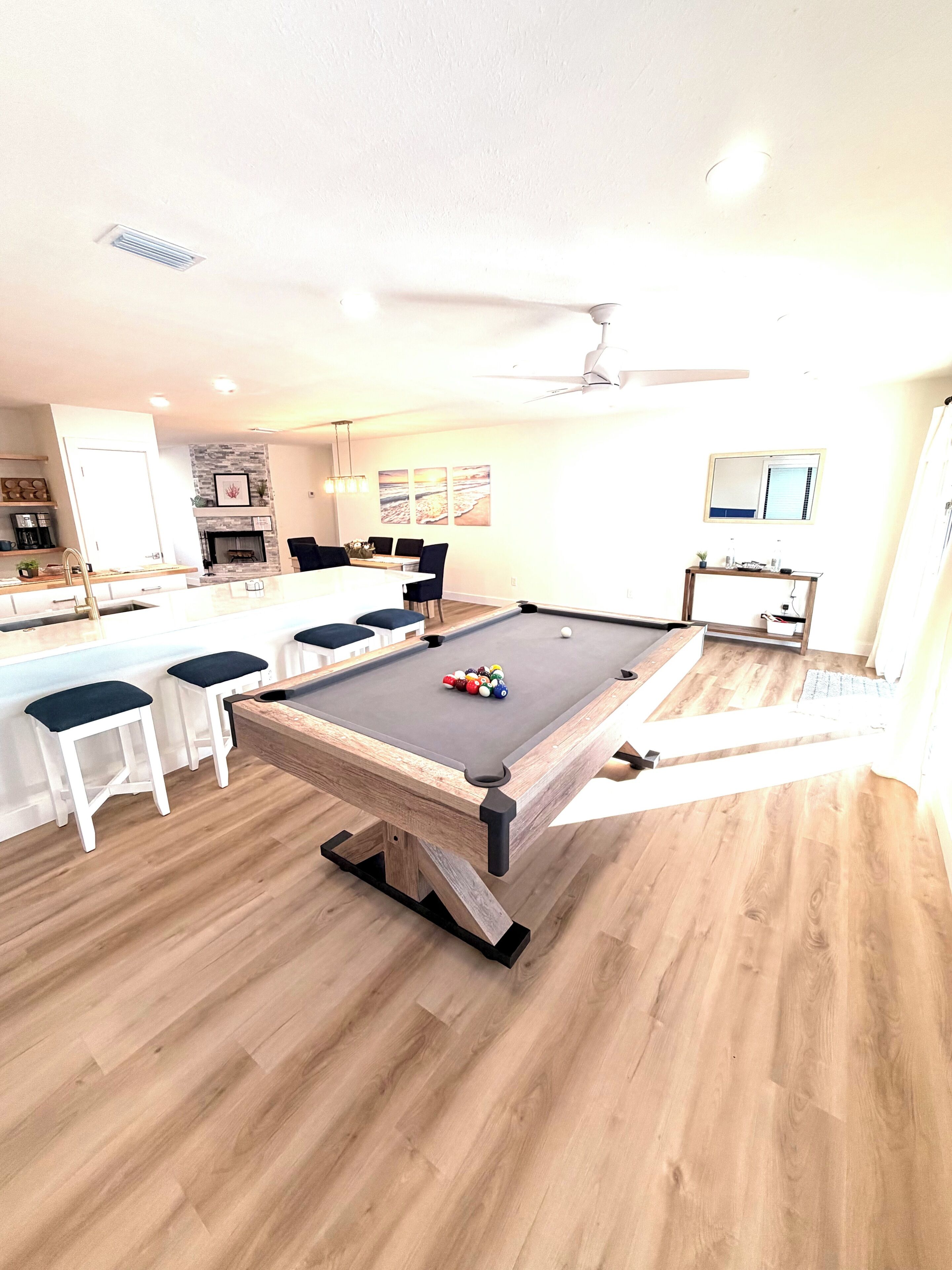 A pool table with balls, a dining area with chairs, and a kitchen area with a coffee machine.