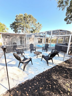 An outdoor seating area with chairs and a table, a covered patio, and a pool. - Coastal Retreat with Pool, Games & Free Kayaks (Sebastian)