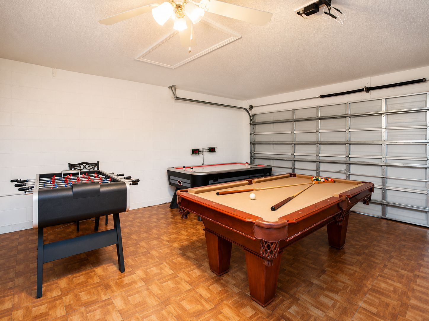Una habitación con mesa de futbolín, mesa de billar y ventilador de techo.