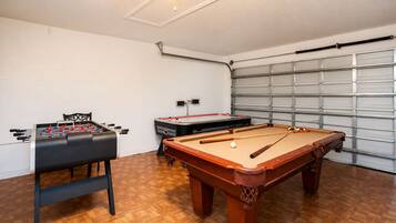 Una habitación con mesa de futbolín, mesa de billar y ventilador de techo.