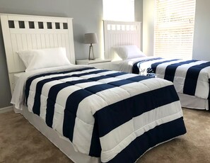 A bedroom with two beds, each with a white headboard and a navy and white striped bedspread. - Luxury 5BR Orlando Villa | Private Pool & Spa | Games Room | Near Disney (Davenport)