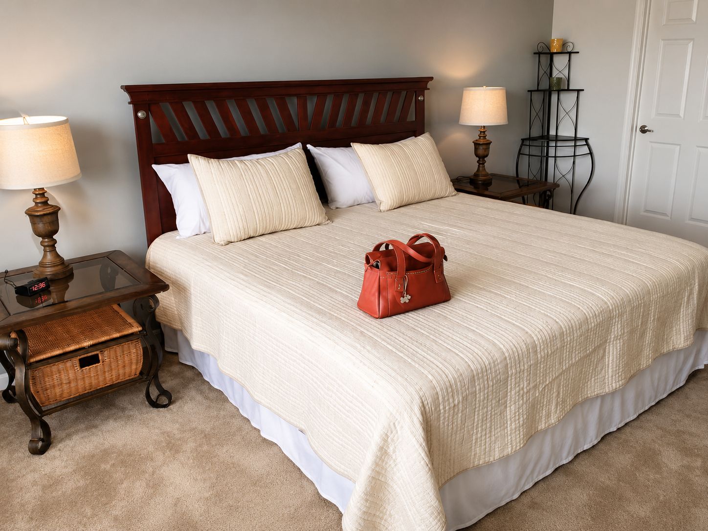 A neatly made bed with a wooden headboard, two bedside tables with lamps, a wicker basket, and a red handbag on the bed.
