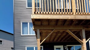 Ein zweistöckiges Gebäude mit einer Holzterrasse und einem überdachten Eingang.